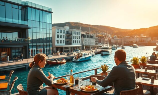 A vibrant scene of Aker Brygge in Oslo, Norway, showcasing its lively waterfront filled with charming restaurants and cafes. In the foreground, a couple of people in modest casual clothing are enjoying a meal at a sunlit outdoor terrace, their table adorned with delicious Norwegian dishes. The middle ground features modern architectural buildings with large glass windows reflecting the turquoise waters of the fjord. Several boats are gently bobbing in the water, adding to the coastal atmosphere. The background displays the picturesque hills surrounding Oslo, bathed in warm, golden hour sunlight, creating a welcoming and relaxed vibe. The image conveys a sense of community and culinary delight, perfect for travelers seeking dining experiences in Oslo.